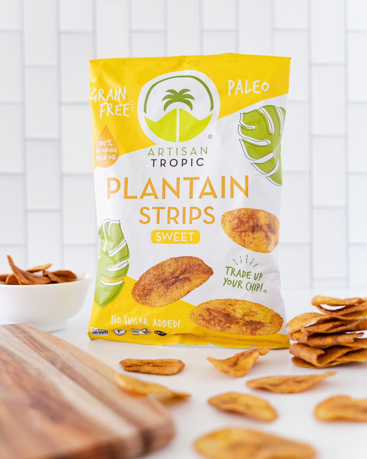 Bag of Artisan Tropic Plantain Strips on a white surface with plantain chips around